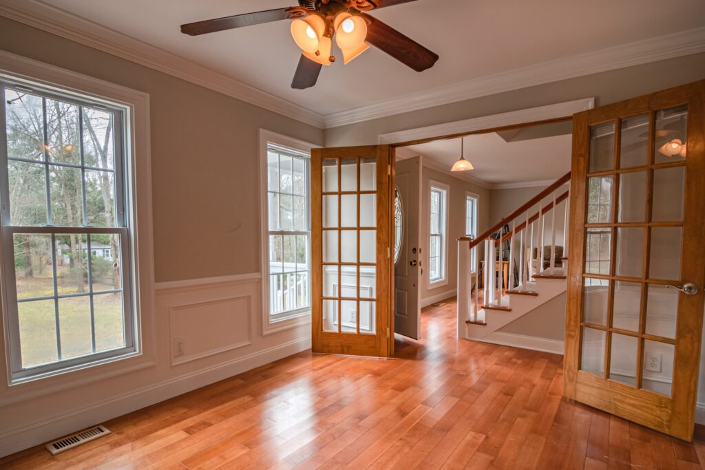 A well-lit room with hardwood floors and a ceiling fan, creating a comfortable and inviting atmosphere.
